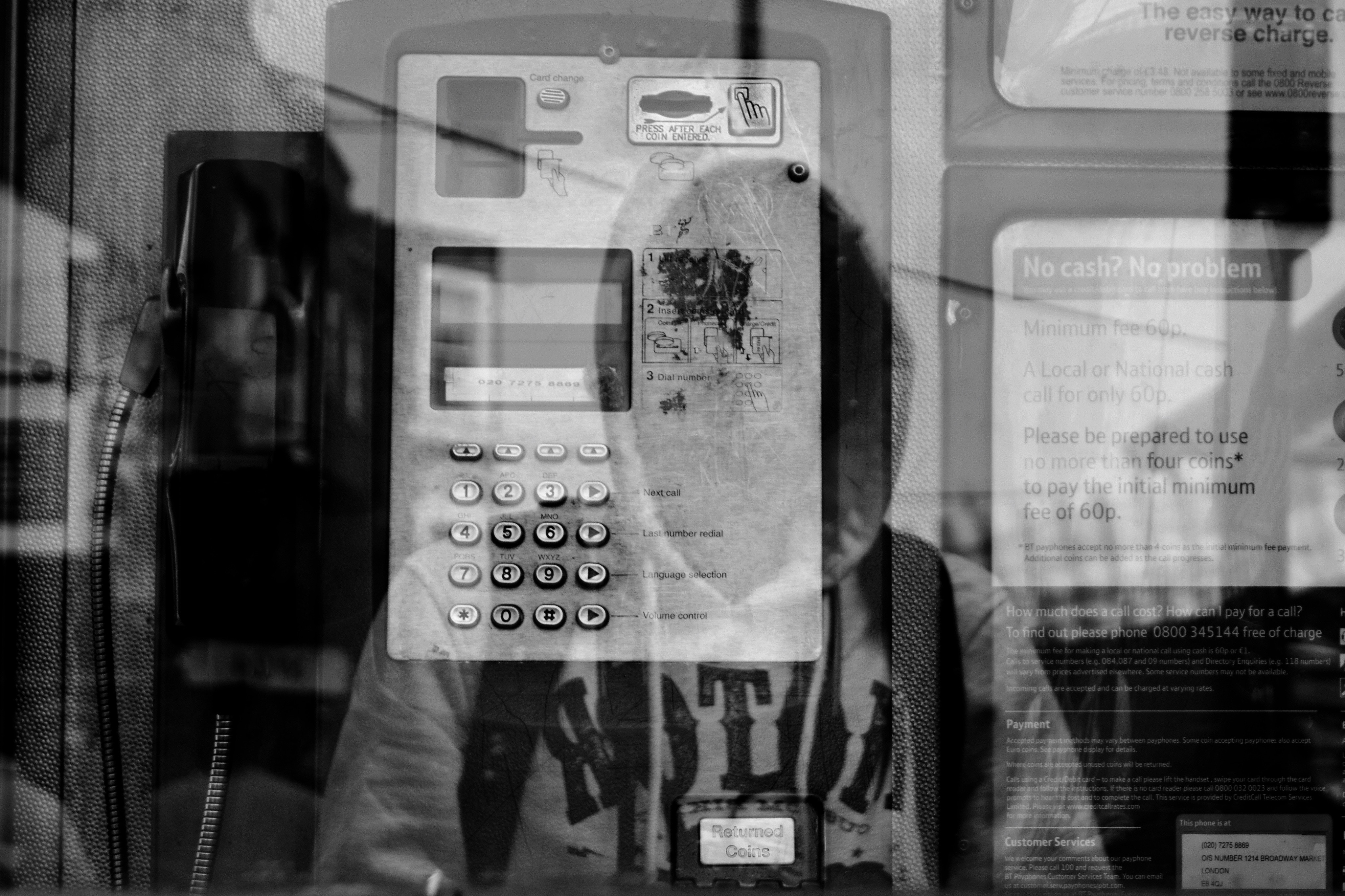 reflection of a person wearing a hoodie; behind the glass is a machine